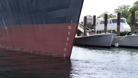 Numbers-line-up-along-bow-of-large-ship-docked-in-front-of-smaller-marine-vessels