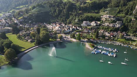 Drone-view-of-idyllic-Swiss-village-nestled-between-a-mountain-and-a-lake