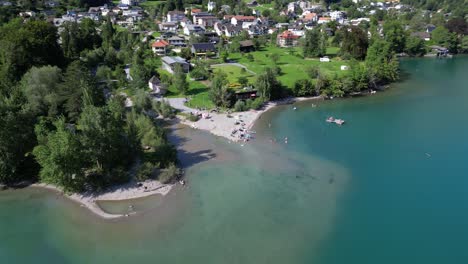 Fly-over-a-side-lake-village-town-in-summer-Switzerland-wonderful-green-landscape-scenic-view-of-beach-yacht-club-boat-in-Walensee-weesen-walenstadt-amden-green-mountain-foothill-shallow-water