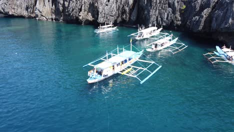 Traditional-Outrigger-Island-hopping-Tour-Boats-anchored-at-the-secret-beach,-El-Nido-Philippines
