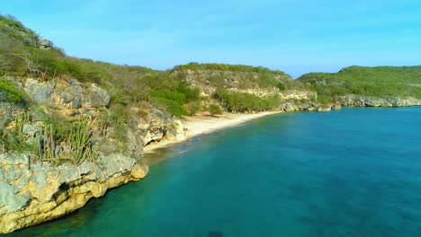 Drone-flyover-caribbean-blue-green-waters-of-San-juan-beach-curacao,-rocky-coastline