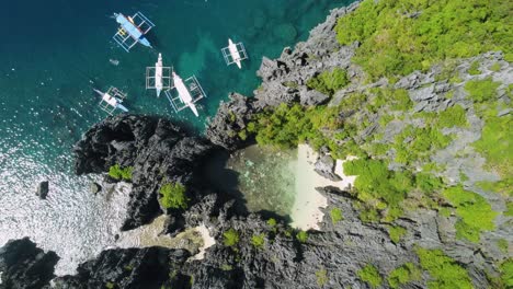 Tourists-swimming-in-hidden-lagoon-of-the-secret-beach-in-El-Nido---Philippines-with-tour-boats-anchored