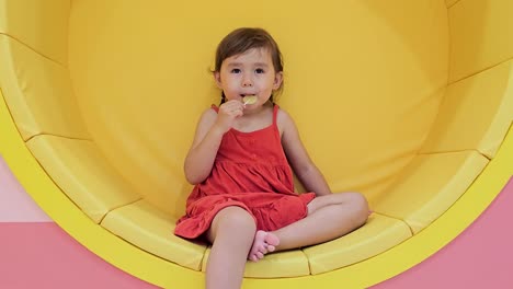 Smiling-Happy-Toddler-Child-Girl-Sucking-Yellow-Lollipop