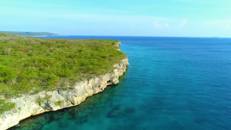Drone-rises-along-caribbean-rocky-coastline-over-clear-water,-perfect-half-land-half-ocean