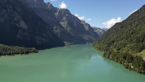 aerial-footage-captures-a-breathtaking-scene-of-a-large-peaceful-lake-surrounded-by-mountains-hills-and-trees-lush-greenery-clear-blue-water-create-a-vibrant-tranquil-atmosphere-perfect-for-adventure