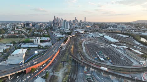 Establishing-pull-away-drone-shot-of-Brisbane-City,-pan-up-shot-during-sunset,-flying-over-the-inner-city-bypass-ICB-road-network