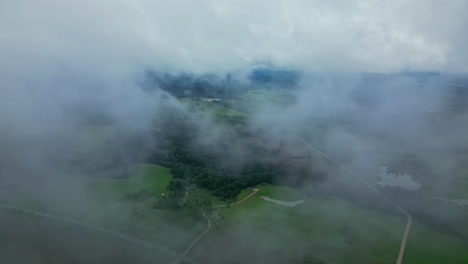 Filmische-Drohnenaufnahmen,-Die-Durch-Wolken-Fliegen,-Mit-Einer-Dramatischen-Landschaft-Darunter
