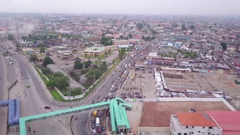 Vista-Aérea-De-Una-Carretera-En-Lagos,-Nigeria,-Con-Vistas-A-Un-Puente-Peatonal-Y-Coches-Y-Camiones-Moviéndose-Afanosamente-Con-Atascos-De-Tráfico.