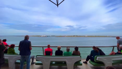 Tourists-sitting-at-ferry-observation-deck-observing-Texel-coastline