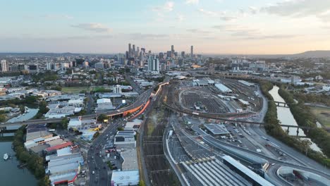Establishing-pull-away-ascending-drone-shot-of-Brisbane-City,-shot-during-sunset,-flying-over-the-inner-city-bypass-ICB-road-network