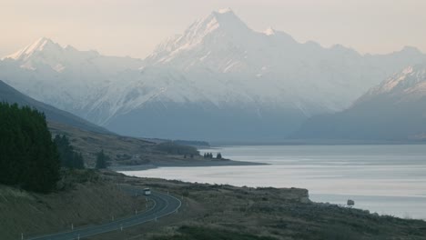 Static-shot-of-a-snow-capped-Mount-Cook-mountain-valley-with-cars-driving-through