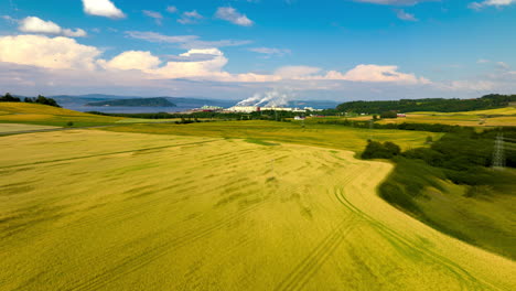 Weite-Landschaft-Aus-Weizenfeldern-Mit-Einem-Industriepark-Im-Hintergrund-In-Auringan,-Norwegen