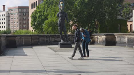 Two-people-walking-next-to-a-statue-of-Berlin