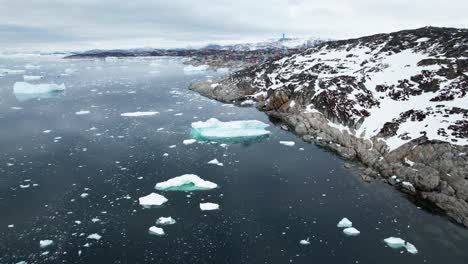 Costa-De-Groenlandia-Con-Iceberg-En-El-Agua-Y-El-Municipio,-Vista-Aérea-De-Drones