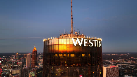Close-up-flight-showing-top-of-Westin-Peachtree-Plaza-Hotel-at-sunset-time-in-Atlanta,-Georgia---Drone-approaching-flight-orbiting