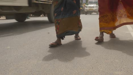 Midday-heat-wave-in-northern-India,-Closeup-of-women-feet-walking-down-the-road-in-windy-hot-climate