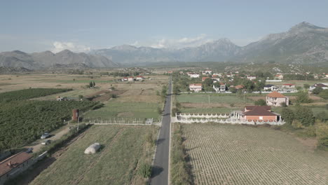 Drohnenschuss-Beim-Flug-über-Das-Weite-Tal-In-Albanien-In-Der-Nähe-Von-Shkoder-Mit-Weinbergen-Darunter-Und-Bergen-Im-Hintergrund-An-Einem-Sonnigen-Tag-Mit-Einigen-Wolken