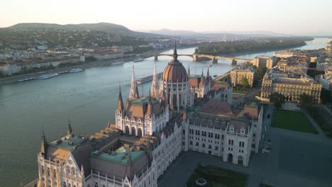 Drone-Flies-Over-Famous-Hungarian-Parliament-Building,-Margaret-Island-in-Background