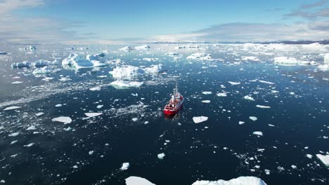 Ship-sailing-surrounded-with-icebergs-in-freezing-ocean,-aerial-view