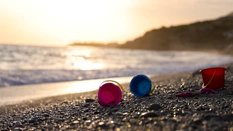 Kinderspielzeug-Am-Strand-Mit-Wellen-Im-Hintergrund-Bei-Sonnenuntergang