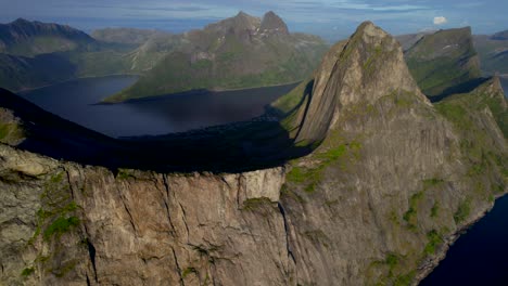 Aerial-panning-shot-of-the-famous-Segla-mountain-on-Senja-Island-Norway-with-a-steep-cliff-face-along-the-sea