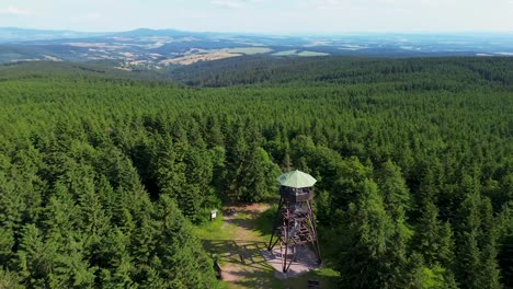 Drone-view-as-it-flies-over-the-trees-and-rotates-near-the-lookout-tower-on-the-mountains-with-the-valley-in-the-background