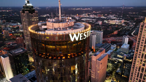 Aerial-orbiting-shot-of-The-Westin-Peachtree-Plaza-Hotel-with-logo-during-sunset-time-in-Atlanta-City,-America