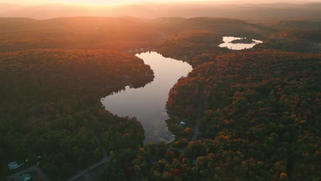 circular-drone-shot-over-typical-canadian-landscape-with-forest-and-lakes-during-fall-season-in-Quebec-Province-at-sunset,-Canada