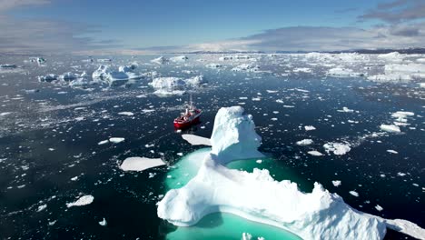 Beautiful-aerial-of-ship-sailing-around-huge-melting-iceberg