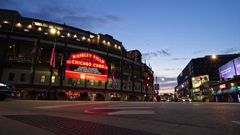 Time-lapse-of-traffic-on-the-streets-in-front-of-the-illuminated-Wrigley-Field-stadium,-dusk-in-Chicago