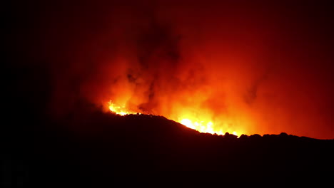 Flaming-wild-fire-inferno,-rolling-over-mountains,-during-nighttime---Time-Lapse