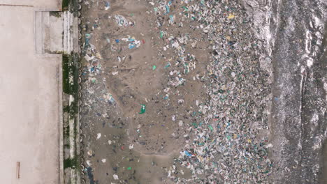 Garbage-washed-up-on-seaside-on-beach-in-Bangkok-Thailand,-aerial-top-down