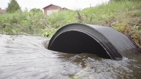 Rainwater-runoff-flows-into-big-black-drainage-pipe-in-countryside