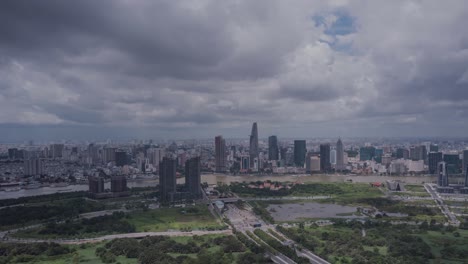 Aerial-hyperlapse-of-Ho-Chi-Minh-City,-Vietnam,-skyline-during-day-time-with-dramatic-highlights-and-shadows,-boats-on-Saigon-river-and-road-traffic-new-residential-and-commercial-development