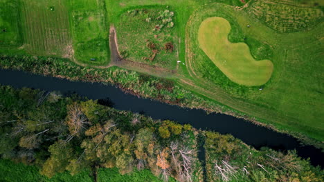 Moving-top-shot-of-a-golf-course-in-Espoo,-Finland,-passing-a-small-river