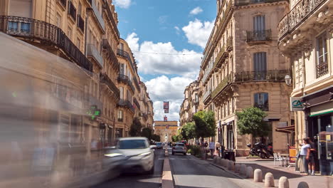 Timelapse-of-Traffic-driving-the-Rue-Foch-in-Montpellier,-and-pedestrians-along-sidewalks