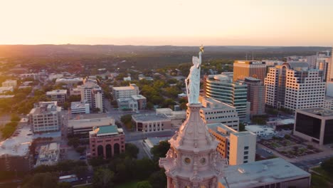 Austin-Texas-State-Capital-Building,-Aerial-Drone-Shot-Circling-the-Liberty-Statue-on-Top-with-Views-of-The-University-of-Texas-at-Austin-and-Downtown-City-Buildings-Skyline-at-Sunset-in-4K