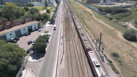 Suburban-Passenger-Train-Moving-in-a-Railway-next-to-a-road-in-Urban-Area,-Lisbon