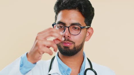 Indian-Hindu-doctor-man-puts-omega-3-tablet-pill-into-mouth-recommends-drugs-vitamin-immunization