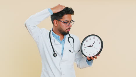 Indian-doctor-man-with-anxiety-checking-time-on-clock,-running-late-to-work,-being-in-delay-deadline