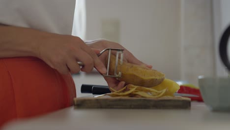 Close-up-of-a-woman-peeling-potatoes-on-the-kitchen-counter