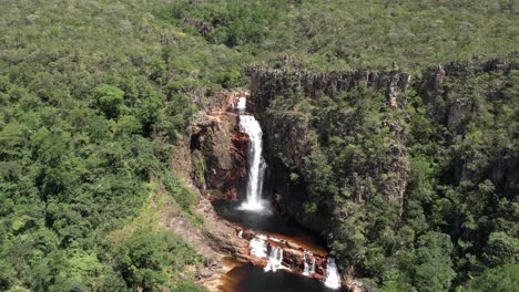 aerial-view-of-the-Catedral-waterfall-and-Macaco-river-in-Complexo-do-Macaco-in-Chapada-dos-Veadeiros-Goiás-Brazil-sunny-day,-waterfall,-rocks-and-vegetation-of-the-cerrado