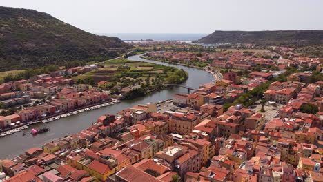 Colourful-Bosa-rooftops-houses-with-view-of-River-Temo-in-Sardinia,-aerial