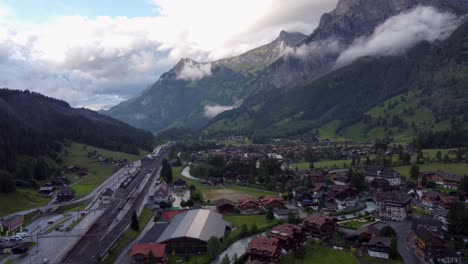 Aerial-Townscape-of-Kandersteg-town-in-Switzerland,-a-Swiss-alpine-Valley-Village-amid-green-Meadows-and-alps-mountains