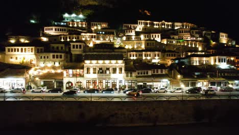 Berat-Nacht:-Touristenvergnügen,-Wenn-Mangalem-Häuser-An-Der-Promenade-über-Dem-Fluss-Osum-Mit-Leuchtenden-Fenstern-Und-Lichtern-Erstrahlen