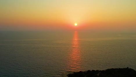 Aerial-View-Of-Golden-Orange-Sunset-Over-Ionian-Sea-With-Pull-Back-Shot-Over-Lefkada-Island