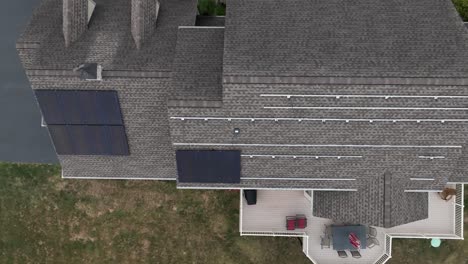 Aufsteigende-Luftaufnahme-Von-Sonnenkollektoren,-Die-Auf-Dem-Dach-Eines-Schindelhauses-Installiert-Werden