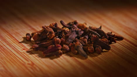 Dried-spice-clove-on-a-wooden-surface-with-dramatic-lighting,-camera-orbiting