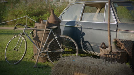 Altes-Und-Rostiges-Auto,-Umgeben-Von-Rustikalen-Landwirtschaftlichen-Geräten-Und-Altem-Fahrrad