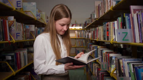 Adolescente-Interesada-En-Leer-Un-Libro-En-La-Biblioteca-De-La-Escuela,-Plano-Medio